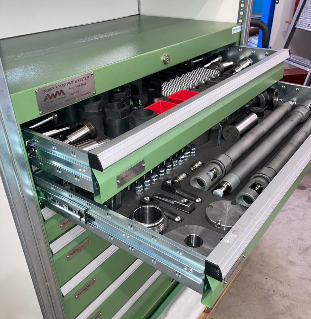 Sortierte Ersatzteile in Werkstattschrank mit Beschriftung.