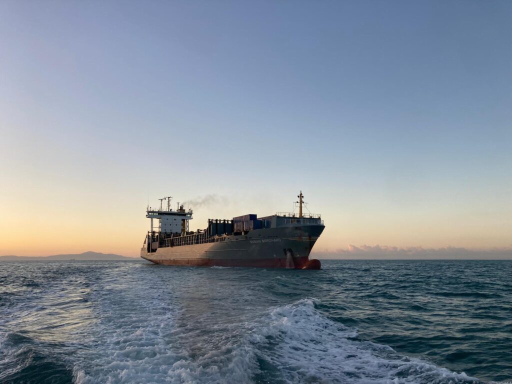 Containerschiff fährt bei Sonnenuntergang auf See.