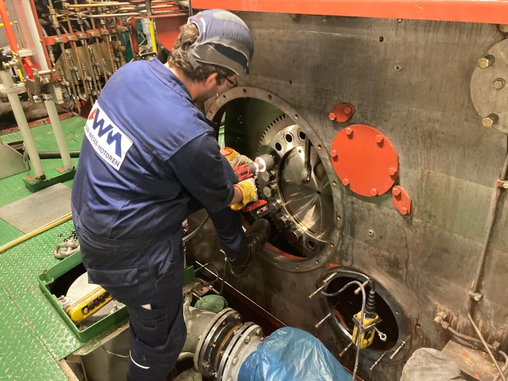 Mechaniker arbeitet mit Drehmomentschlüssel am Schwungrad.