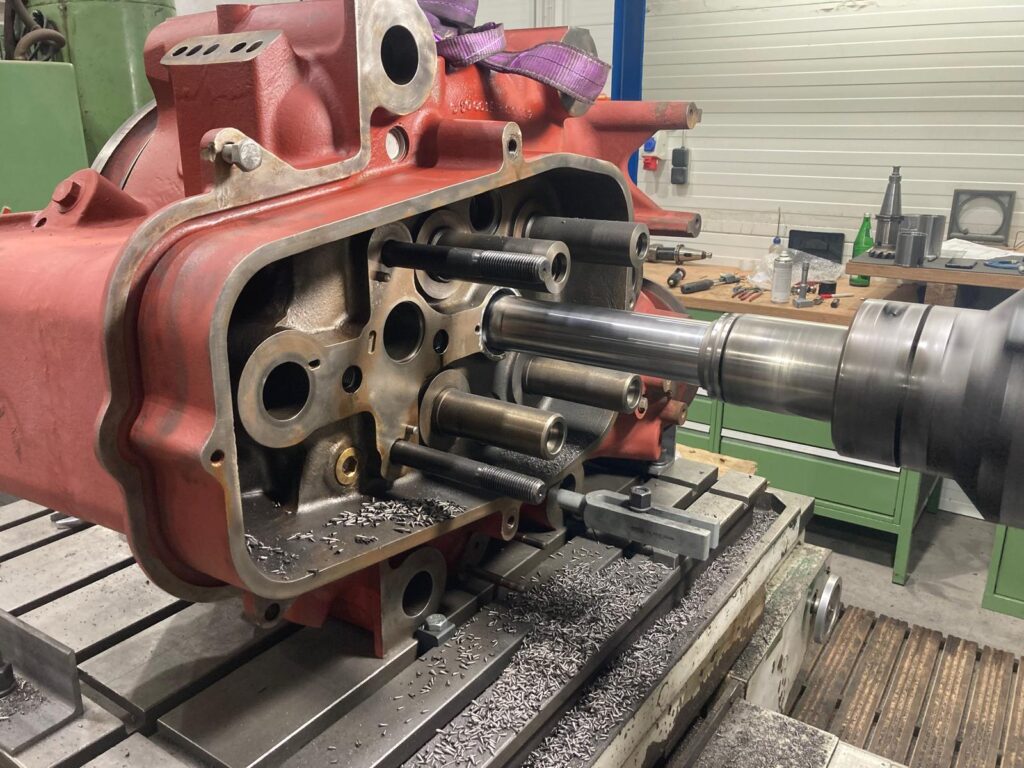 Fräsbearbeitung an rotem Getriebegehäuse.